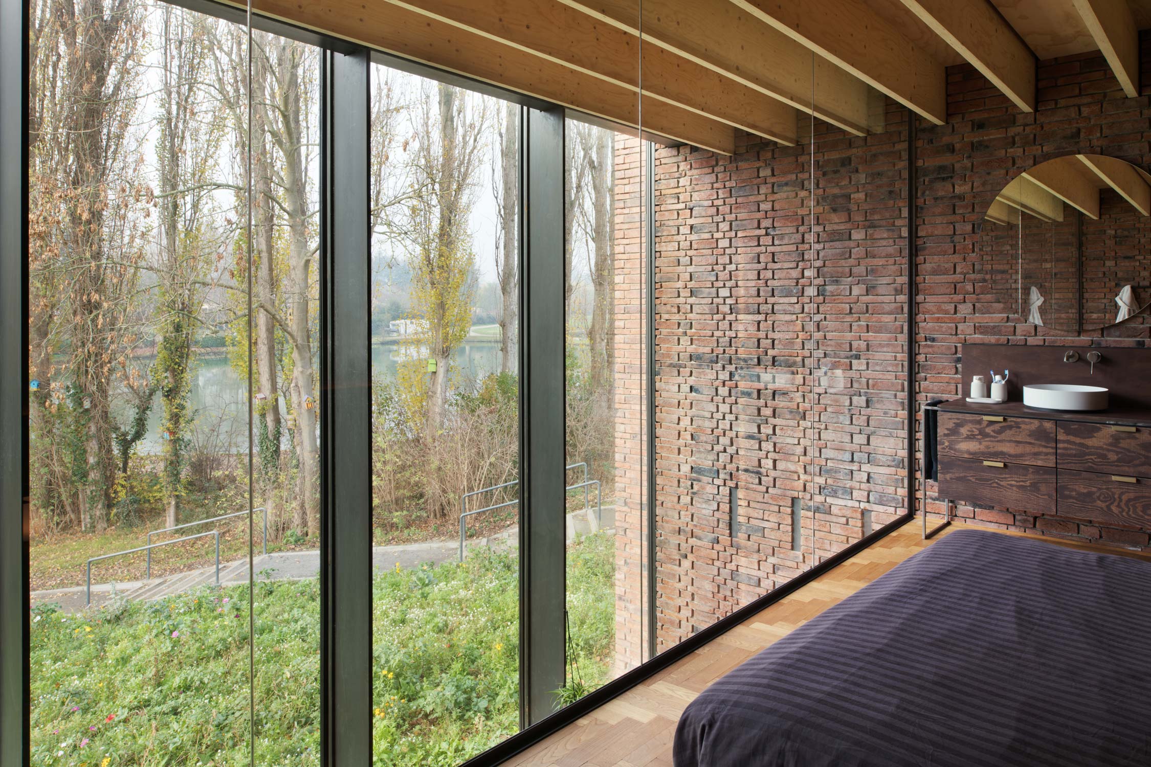 ruime slaapkamer met natuurlijke lichtinval dankzij grote zwarte aluminium ramen met grote glaspartijen