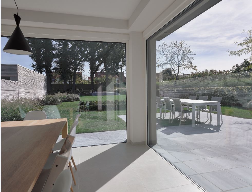 open eetruimte met grote witte aluminium ramen met zicht op terras en tuin