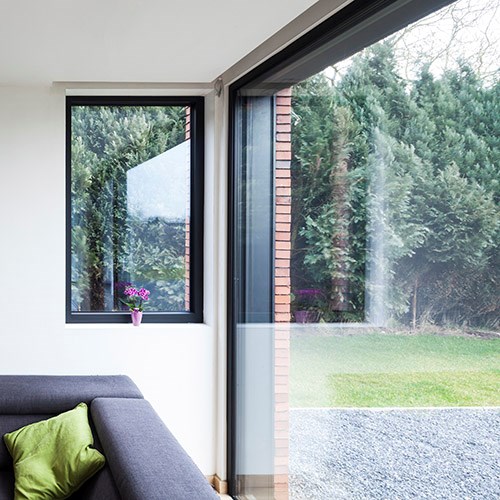 Groot raam met zwarte aluminium profielen met zicht op tuin