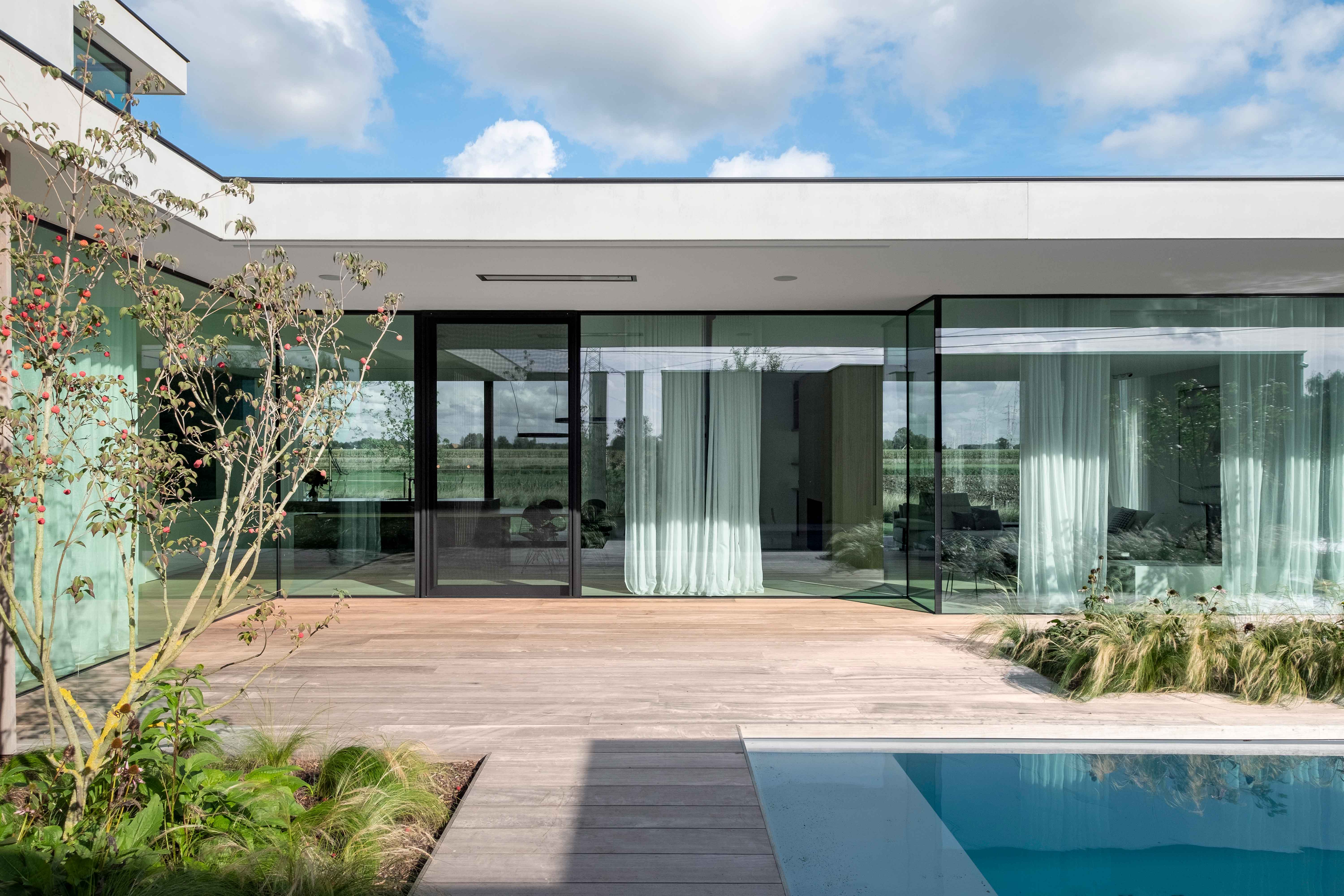 villa blanche avec de grandes fenêtres avec des profilés en aluminium noir donnant sur la piscine